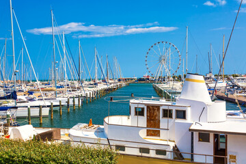 Obraz premium Summer view of pier with ships, yachts and other boats with ferris wheel in Rimini, Italy