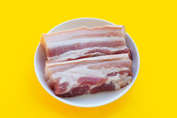 Obraz premium Streaky pork in white plate on yellow background.