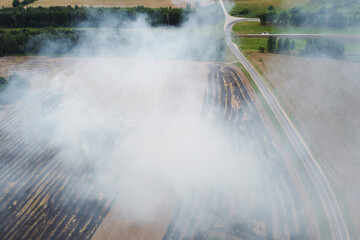 Aerial view of burning field with smoke and road