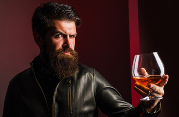 Expensive drink. Male in leather jacket drinking brandy or cognac. Bearded man with glass of whiskey.