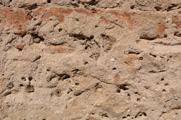 Dilapidated mortar with little holes and red brick on an old house wall. Close up and copy space. Retro background and texture concept