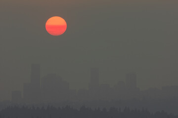 Heavy wildfire smoke surrounds Seattle with orange sun at sunset
