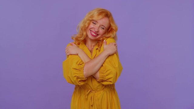 Come to me, I want to embrace you. Redhead stylish girl in yellow dress spread hands and give hug to you. Pleasant expression, love feelings. Young woman on purple background. People sincere emotions