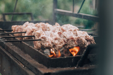 Raw meat on skewers is cooked on charcoal grill, cooking barbecue outdoors