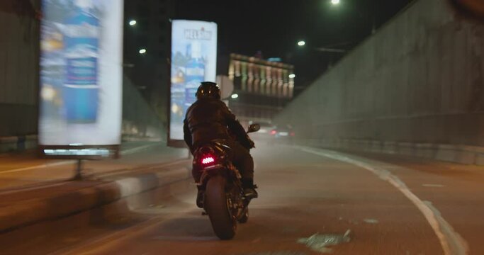 Biker with super sport motorcycle .  All in black Motorcyclist riding fast on city road at night . Motorcycle adventure lifestyle . Fast riding of black biker . Shot on ARRI ALEXA Cinema Camera .