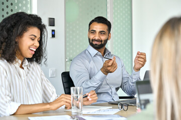 Happy young female Afro American businesswoman and indian executive manager working together. Diverse multiethnic professional group discussing financial business plan at office board room meeting.