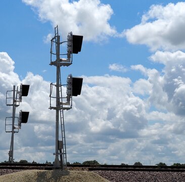 Modern railroad signals against a sky of cumulus clouds