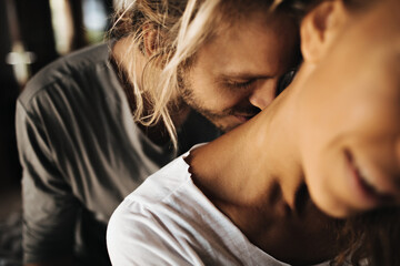 Handsome man with long hair gently kisses neck of his beloved - obrazy, fototapety, plakaty