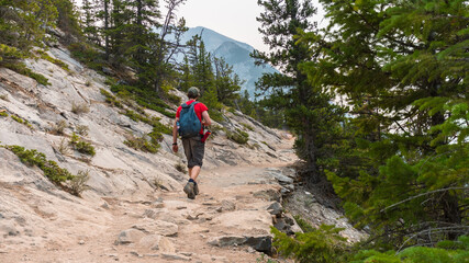 Fototapeta premium Hiker climbing up a rocky mountain path in Banff National Park nature background. Hiking trails and healthy lifestyle concept