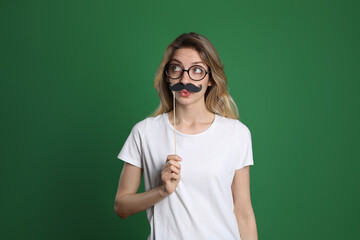 Funny woman with fake mustache on green background