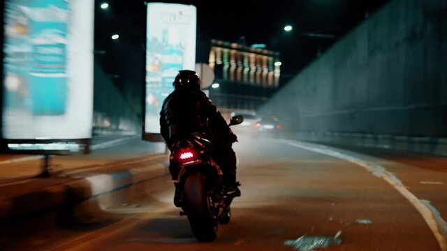 Biker with super sport motorcycle .  All in black Motorcyclist riding fast on city road at night . Motorcycle adventure lifestyle . Fast riding of black biker . Shot on ARRI ALEXA Cinema Camera .