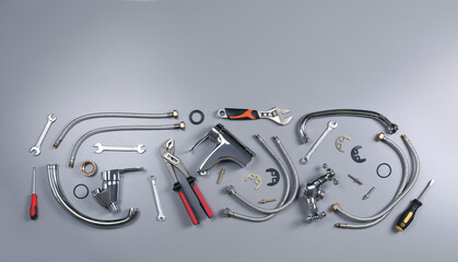 Parts of water tap and plumber tools on grey background, flat lay