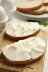 Obraz na płótnie Canvas Bread with cream cheese on wooden table, closeup