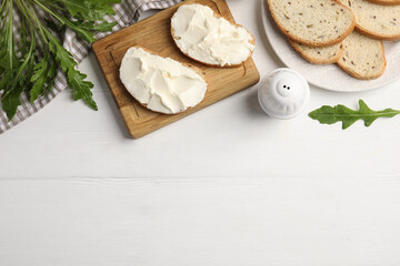 Fototapeta na wymiar Bread with cream cheese on white wooden table, flat lay. Space for text