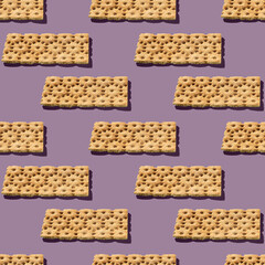 Photo in the form of a seamless pattern. Orange color crispbreads for healthy food with shadows on a colored lilac background.