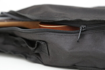 Small brown wooden ukulele guitar in black cover.
