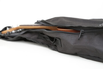 Small brown wooden ukulele guitar in black cover.
