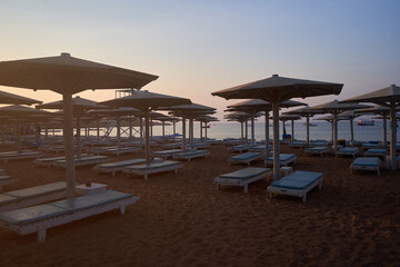 Umbrellas and sun loungers at luxury tropical resort on coral beach in the Red Sea. Resort complex on Red Sea. Typical resort beach.