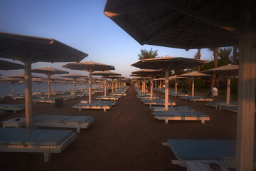 Umbrellas and sun loungers at luxury tropical resort on coral beach in the Red Sea. Resort complex...