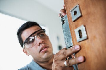 Close-up of male hands repair or installing a metal door lock. - obrazy, fototapety, plakaty