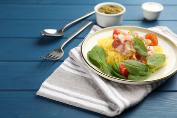 Tasty spaghetti squash with bacon and basil served on blue wooden table, space for text