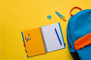 School backpack with colorful school supplies on yellow background. Banner design