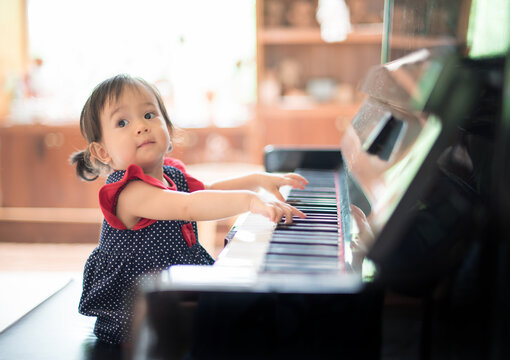 Little Asian cute girl playing piano