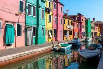 Fototapeta na wymiar Street with colorful buildings in Burano island, Venice, Italy. Scenic canal and colorful architecture.