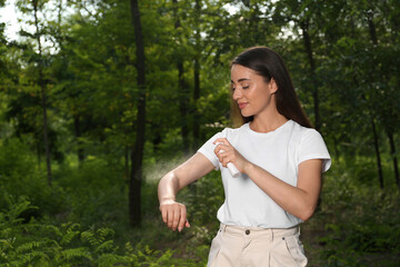 Woman applying insect repellent on arm in park. Tick bites prevention
