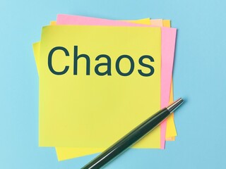 Text CHAOS written on sticky note with a pen.
