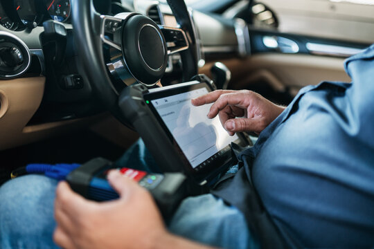 Car diagnostic. Technical inspection, car electronics. A Latin man holds a digitizing device.