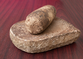grinding stone, pestle on wooden texture. A traditional rock grinder to mash spices and herbs.