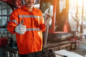 Thumbs up of excavator repair technician with large iron wrench in a hand, Powerful Professional...