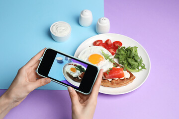 Woman taking photo of delicious breakfast on color background, closeup