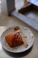 Fresh french croissant on white ceramic plate on wooden table