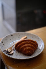 Fresh french croissant on white ceramic plate on wooden table