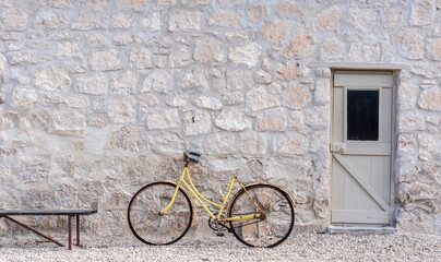 Rusty, old yellow bicycle in front of a stone wall, Rural South Australia