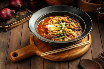 Korean beef ramen spicy noodle soup with chopsticks on a wooden background