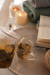 Pouring freshly brewed tea into cup at table in room, closeup. Cozy home atmosphere