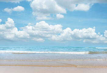 Fototapeta na wymiar Sand beach on blue sea, white wave under white clouds, pastel blue sky