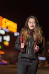 Portrait of a young beautiful dark-haired girl in the night city, close-up.