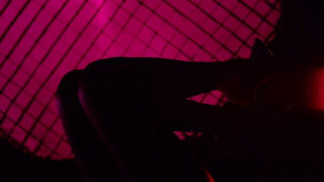 Close up of the legs beautiful sexy woman posing and dancing in knee high heels . Silhouette of female legs in high-heeled shoes on a background of lilac light . Holding up woman's legs . Slow Motion 