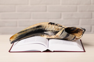 Shofar and open Torah book on white wooden table. Rosh Hashanah holiday attributes