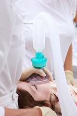 The resuscitator holds an oxygen mask on the child's face. General anesthesia. Preparing for...