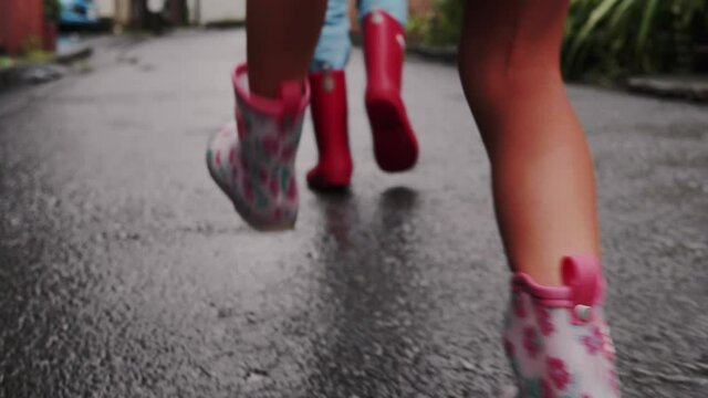 雨の日に長靴を履いて傘をさして歩く子供