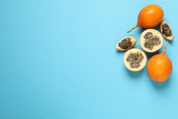 Delicious ripe granadillas on light blue background, flat lay. Space for text