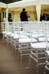 Glass chairs stand in a row in a beautiful wedding outing ceremony