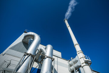 Biofuel boiler chimneys on a blue sky background.  Electrostatic precipitator in the foreground
 - obrazy, fototapety, plakaty