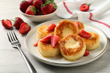 Delicious cottage cheese pancakes with strawberries and honey on white wooden table