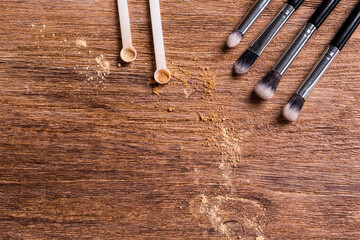 Mineral powder for face and a brushes for powder and visage on wooden background with copy space. Eco friendly and organic cosmetics.